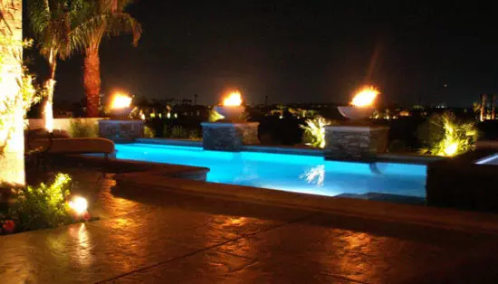 fire bowls next to pool at night